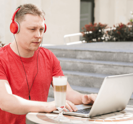 Man working on a laptop, ensuring compliance with accessibility and providing support for quality audio description services.