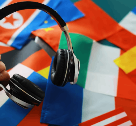 Headphones with international flags, symbolizing multilingual audio descriptions in Spanish, English, Russian, and more.