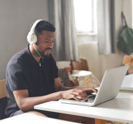 A man working on laptop, providing high-quality audio description services for inclusive content, ensuring accessibility.