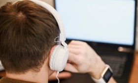 Focused person typing Chinese captions on computer, wearing headphones for work.