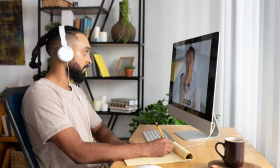 Person with headphones watches video on computer with closed German captions.