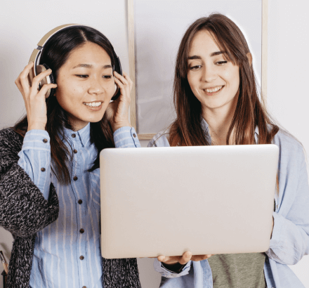 Two diverse women working on a laptop, illustrating professional Japanese subtitling services by certified linguists.