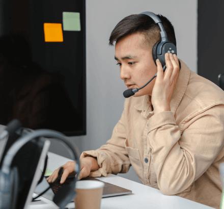 A man hearing the audio on a headset using a laptop for Russian captioning services tailored for the media industry.