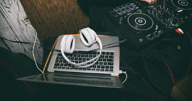 Headphones laced on a laptop with DJ decks